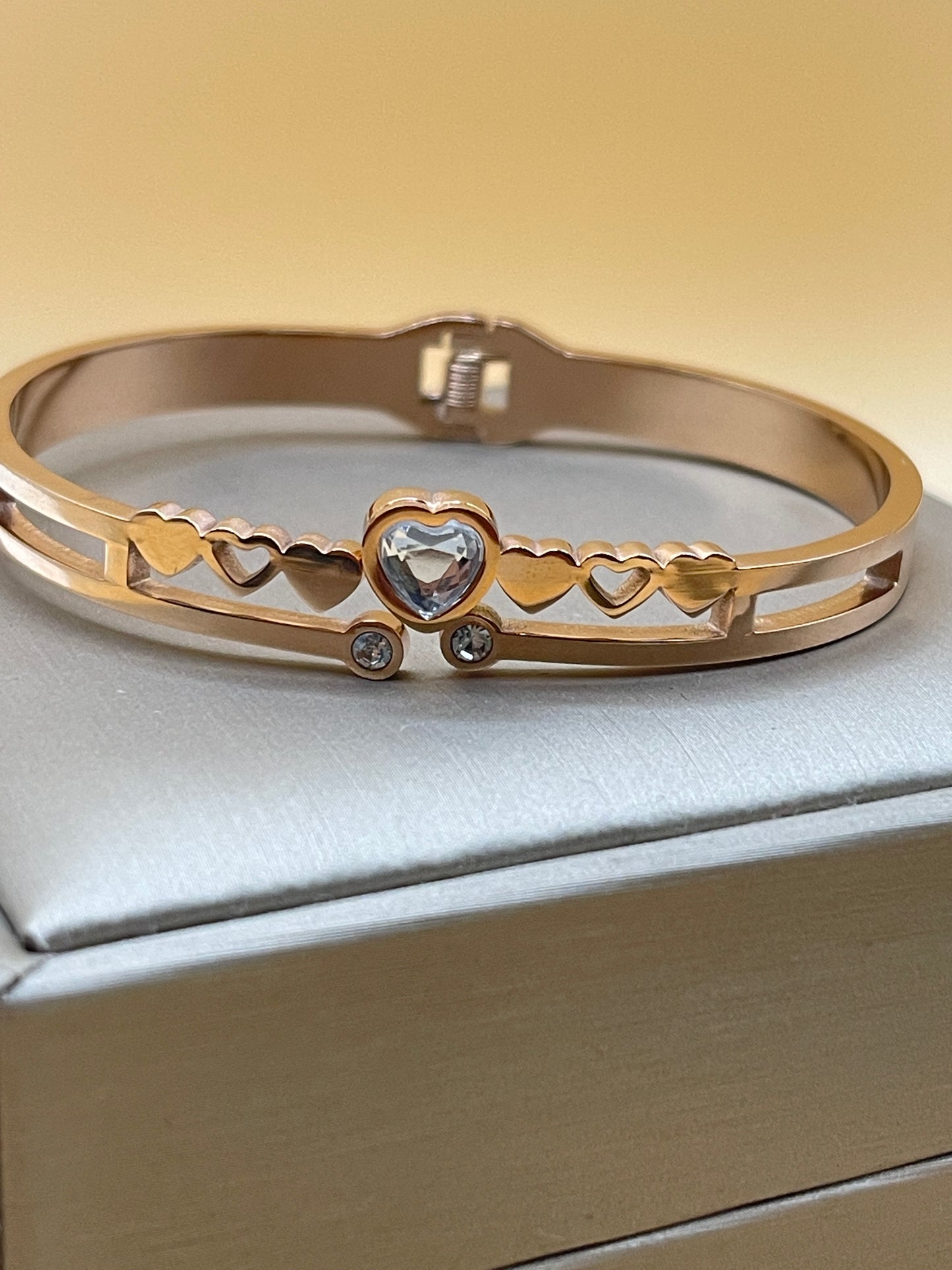 Rose Gold bangle with gemstones on a light gray background