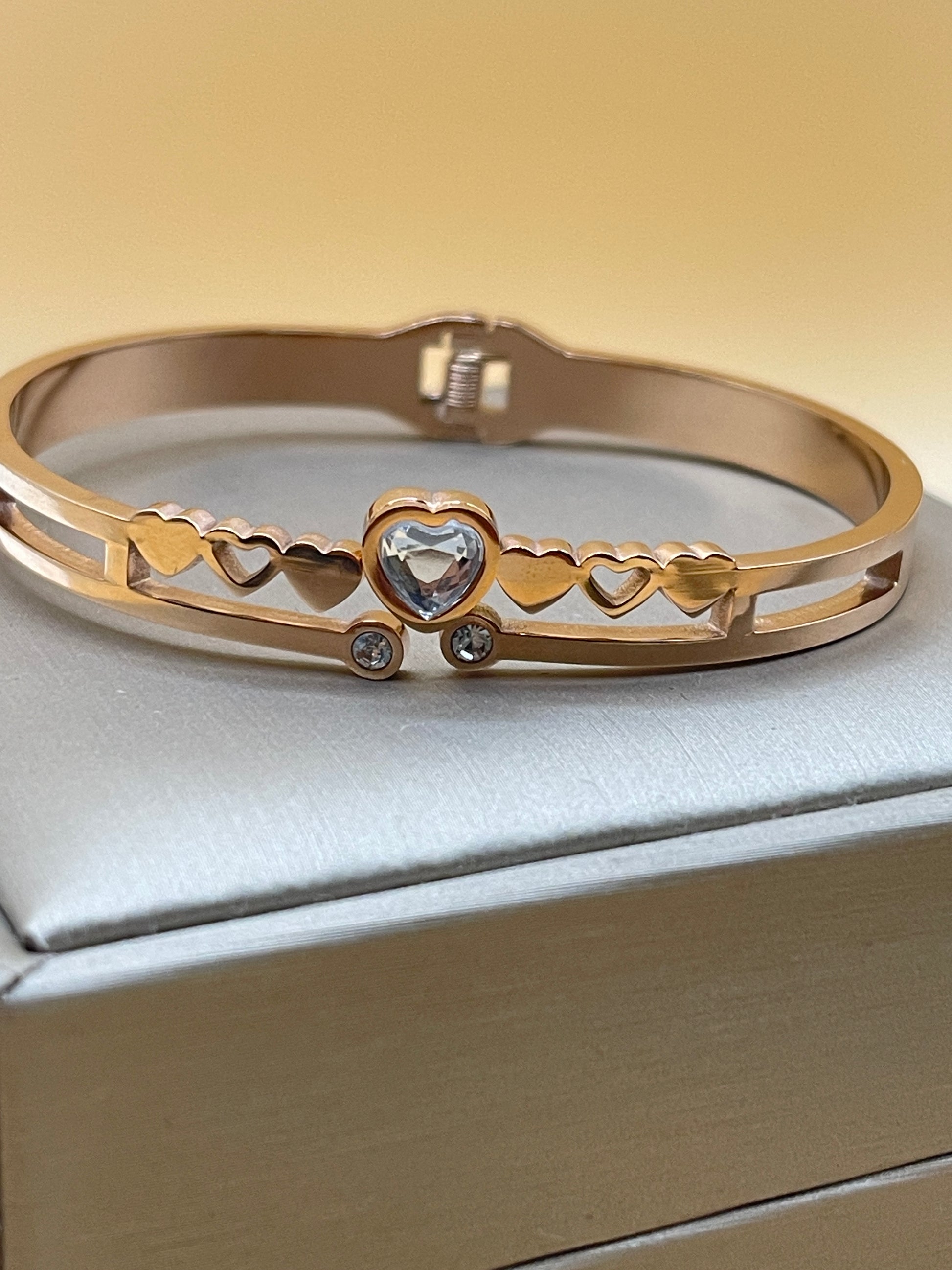 Rose Gold bangle with gemstones on a light gray background