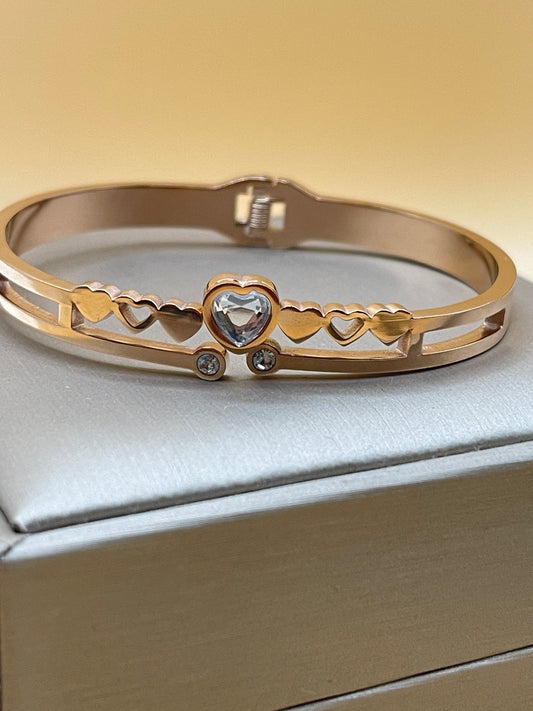 Rose Gold bangle with gemstones on a light gray background