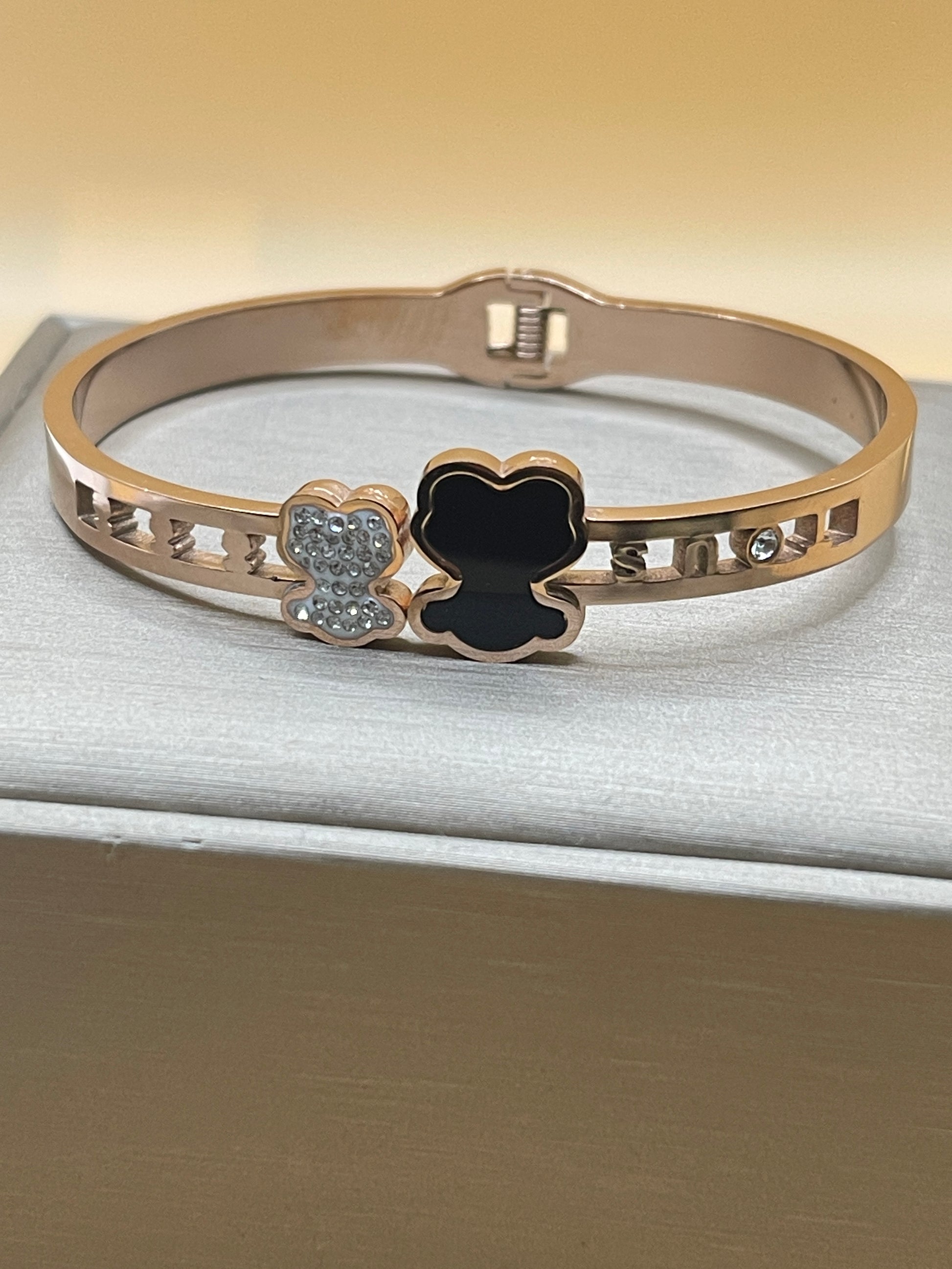 Rose Gold bracelet with black clover and diamond accents on a neutral background