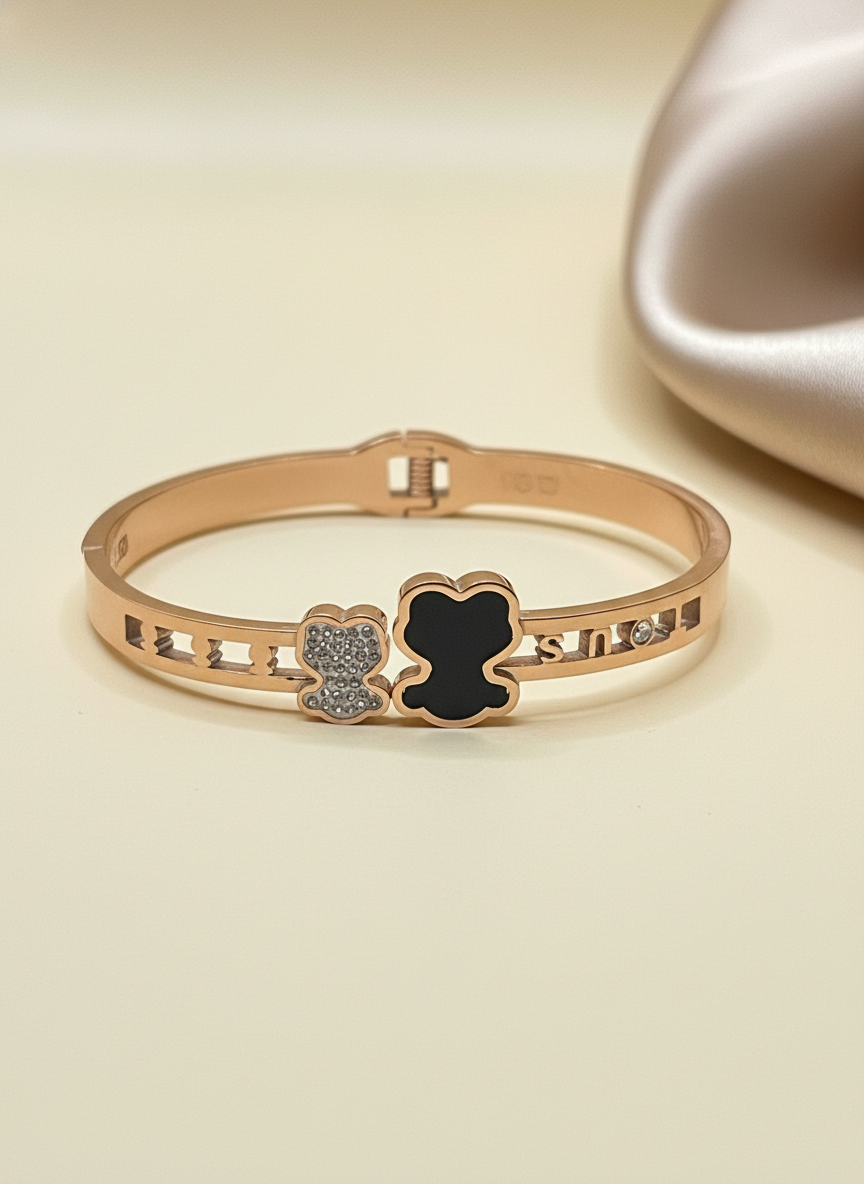 Rose gold bracelet with black heart and diamond design on a beige background