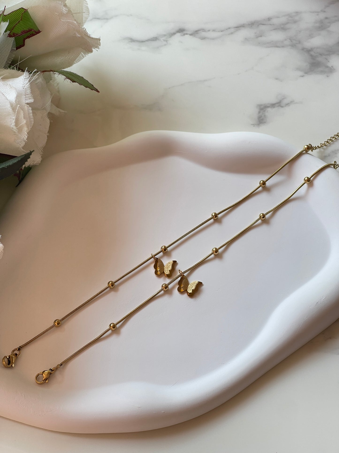 Gold necklace on a white dish with a marble background