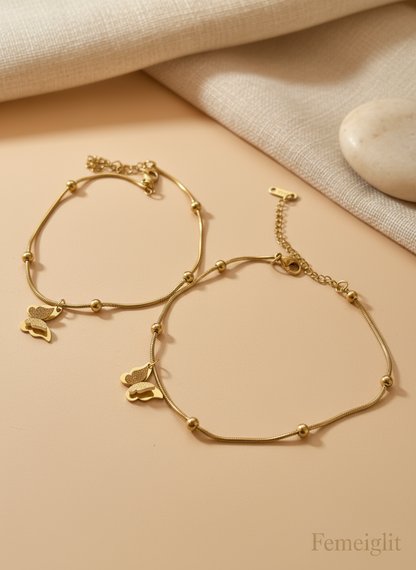 Gold bracelet with small animal charms on a beige surface, brand 'Femeiglit' visible.