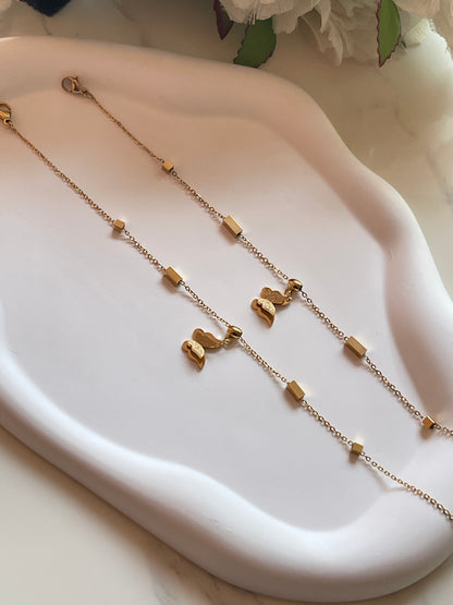 Gold necklace with butterfly pendants on a white dish