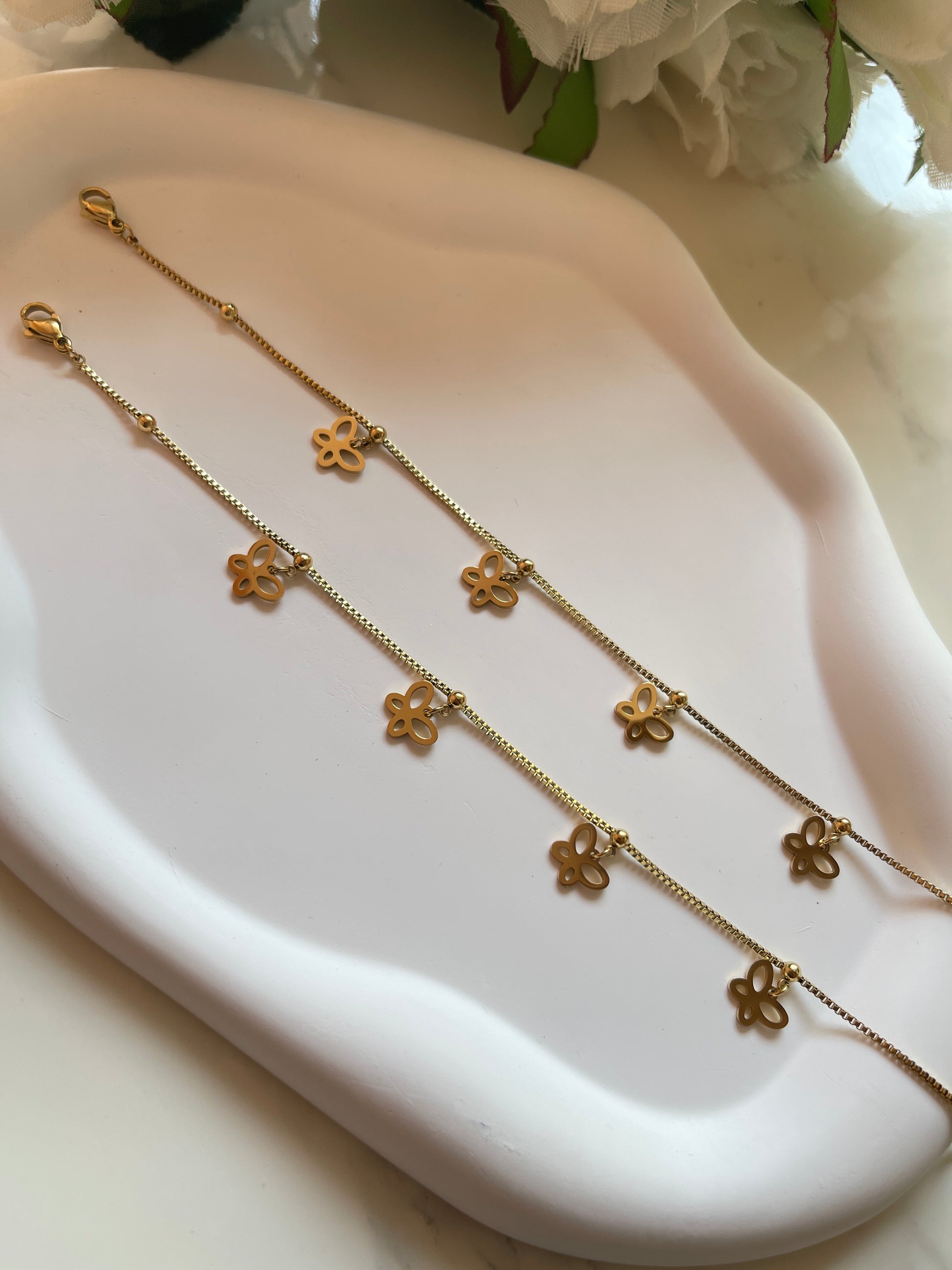 Gold necklace with floral pendants on a white dish