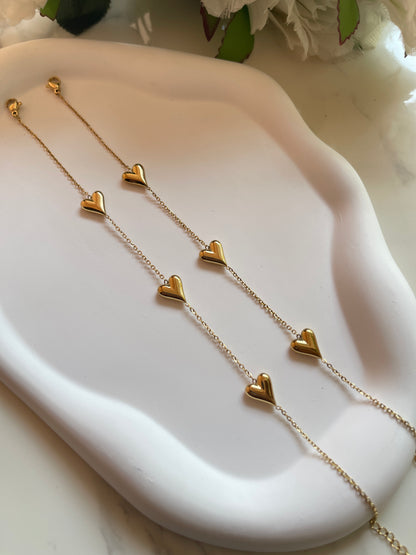 Gold heart-shaped necklace on a white dish with a floral background