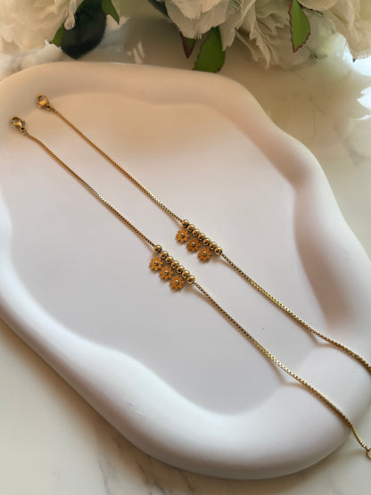 Gold necklace on a white dish with flowers in the background