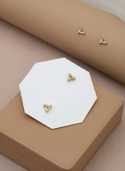 Gold triangle earrings on a branded card with a soft background